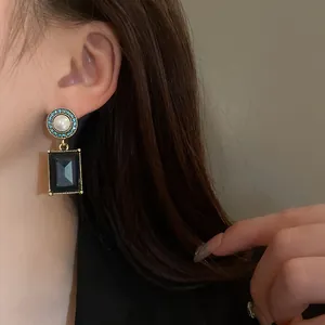 Close-up of vintage French style earring featuring a pearl and black square gemstone
