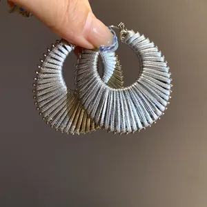 Close-up of large silver hoop earrings with metallic thread wrap texture detail