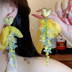 Detailed view of sweet yellow chiffon flower earrings with beaded heart charms detail.