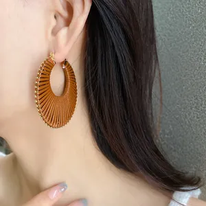 Close-up of brown woven hollow hoop earrings on model with high-end textured finish