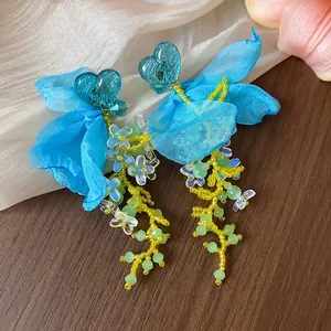 Close-up of sweet blue heart resin earrings with chiffon petals and floral beads.