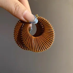 Detail view of large brown textured hoop earrings with a pleated gold-toned radial design.