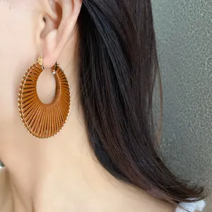 Detailed view of a stylish brown textured woven hoop earring worn by an Asian model