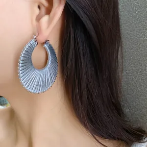 Detail shot of silver-tone hoop earrings showing intricate woven metallic thread texture.