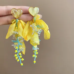 Detailed macro view of yellow heart resin earrings with chiffon fabric and beaded tassels