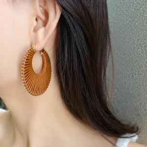 Detailed view of a brown woven round hoop earring worn by a model in a stylish close-up shot