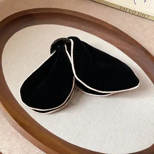 Detailed view of a black velvet triangular wing hair claw clip with cream piping detail