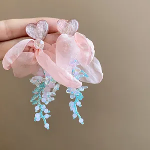Detailed view of pink chiffon flower earrings with resin hearts and beaded tassels.