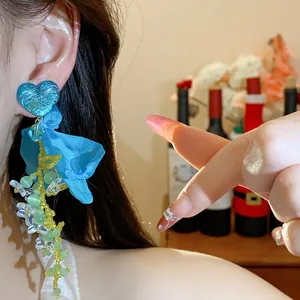 Close-up view of blue resin heart earrings with elegant chiffon flowers and bead tassels.