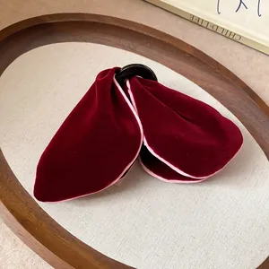 Detailed close-up of a luxury burgundy velvet triangle hair claw clip featuring pink trim