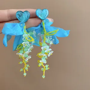 Detail of blue heart resin earrings with chiffon petals and beaded tassels, sweet style.