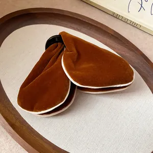 Close-up of elegant brown velvet triangular hair clips on a wooden tray.
