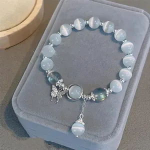 Close-up detail of white cat's eye stone beaded bracelet featuring a sparkling butterfly charm