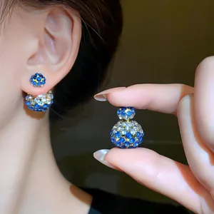 Close-up view of double-sided rhinestone stud earrings with blue and clear stones