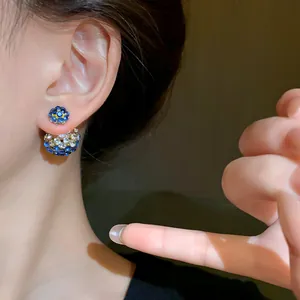 Macro detail view of elegant blue rhinestone front-back earrings worn by a model