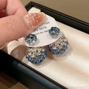 Detail shot of double-sided stud earrings featuring blue and clear rhinestones.