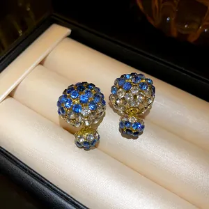 Detailed view of blue and white rhinestone double-sided earrings in a jewelry box