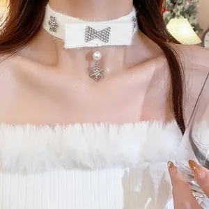 Κοντινό πλάνο λευκού βελούδινου choker με κρυστάλλινο φιόγκο και μενταγιόν χιονονιφάδα