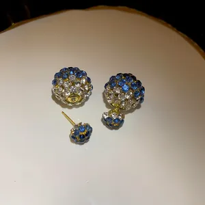 Close-up detail of double-sided stud earrings featuring blue and clear pavé rhinestones
