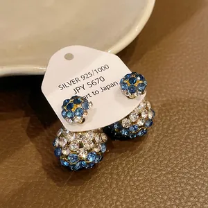 Macro view of elegant double-sided stud earrings with blue and white crystal spheres.