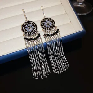 Close-up of vintage silver tassel earrings with floral pattern and black beads