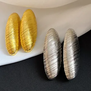 Macro view of vintage textured gold and silver oval stud earrings on silk background