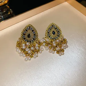 Detailed macro view of vintage gold earrings with intricate metalwork and elegant pearl tassels.