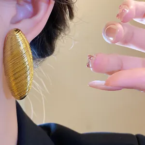 Detailed view of vintage oval gold earrings featuring a textured ribbed design on the ear
