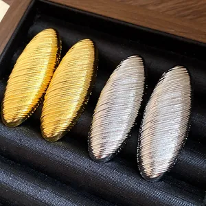 Detailed macro view of vintage oval stud earrings with textured gold and silver finishes