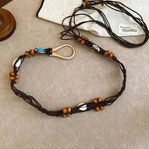 Close-up of handmade ethnic woven belt featuring natural wood beads, shells and turquoise