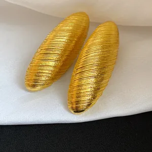 Macro view of vintage oval gold earrings with textured brushed finish