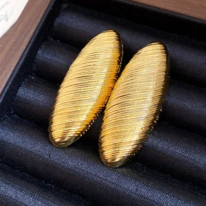 Close-up of elegant gold oval stud earrings with horizontal texture in a jewelry box