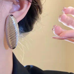 Close-up view of a vintage silver textured oval stud earring worn on model's ear.