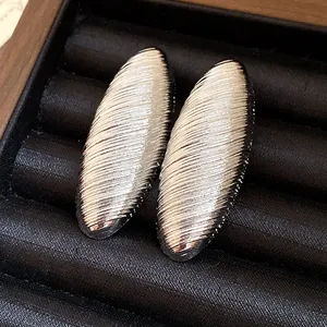 Detail of vintage oval silver-tone earrings with textured ribbed surface on black jewelry tray.