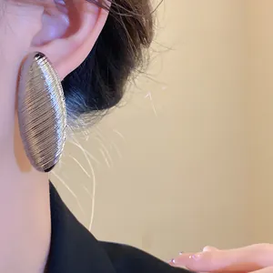 Detailed close-up view of vintage silver oval textured stud earrings worn for elegant look