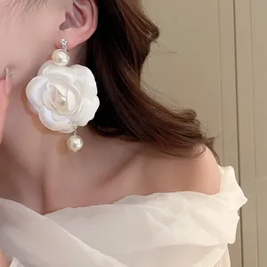 Nahaufnahme eines eleganten weißen Kamelien-Ohrrings mit Perlen, von Model getragen