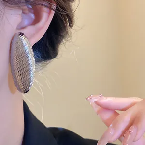 Detailed close-up of retro silver-tone oval stud earrings with ribbed metallic texture
