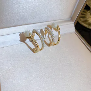 Detailansicht eleganter goldfarbener Perlen- und Blumenohrringe in einer Geschenkbox