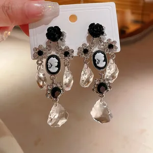 Dettaglio di orecchini vintage in stile barocco con rose nere e cammei in bianco e nero.