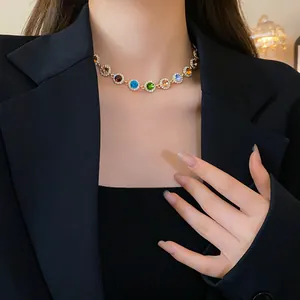Detailansicht einer stilvollen bunten Strass-Halskette, getragen über einem schwarzen Blazer.