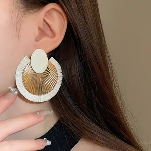 Primo piano di orecchini rotondi retrò in rafia bianca intrecciata indossati da una modella