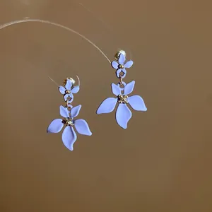 Eleganti orecchini a sospensione a fiore viola con finitura opaca e dettagli dorati.
