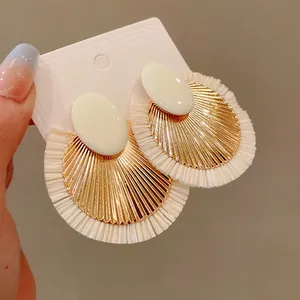 Dettaglio di orecchini in rafia con metallo dorato e frange a ventaglio vintage