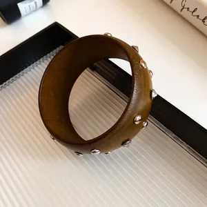 Detailansicht eines vintage braunen Holzarmreifs mit dekorativen Metallnieten