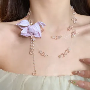 Close-up detail of a double-layer necklace with a purple fabric flower and pink beads.