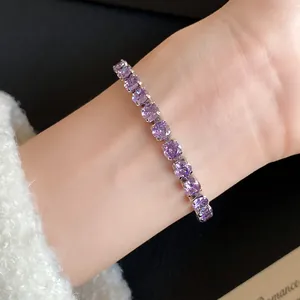 Detailed close-up view of an elegant purple zircon bracelet worn on wrist with white sweater