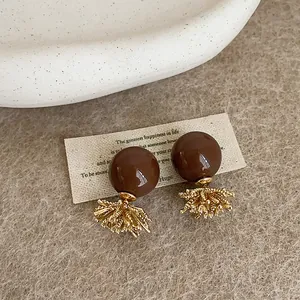 Primo piano di eleganti orecchini sferici marroni con nappe dorate stile fuochi d'artificio