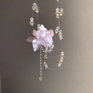 Close-up of double-layer fabric flower pendant and crystal beads on a delicate necklace
