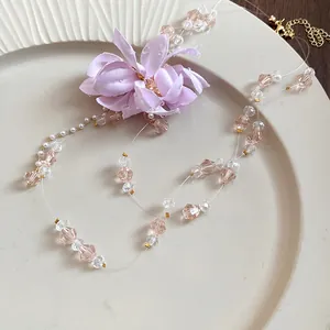 Close-up of double-layered necklace with purple fabric flower and pink crystal beads