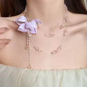 Close-up of double-layered necklace with purple fabric flower and pink crystal beads.